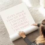 affiche beige clair avec typographie orange pastel disant je maime jaime mon cor au sol.webp