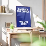 affiche bleue avec le texte embrace the chaos et we live here en blanc casse sty bureau.webp