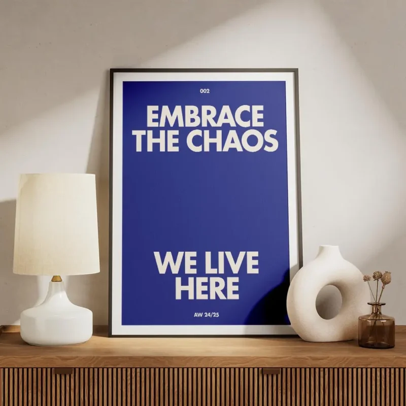 affiche bleue avec le texte embrace the chaos et we live here en blanc casse sty meuble.webp