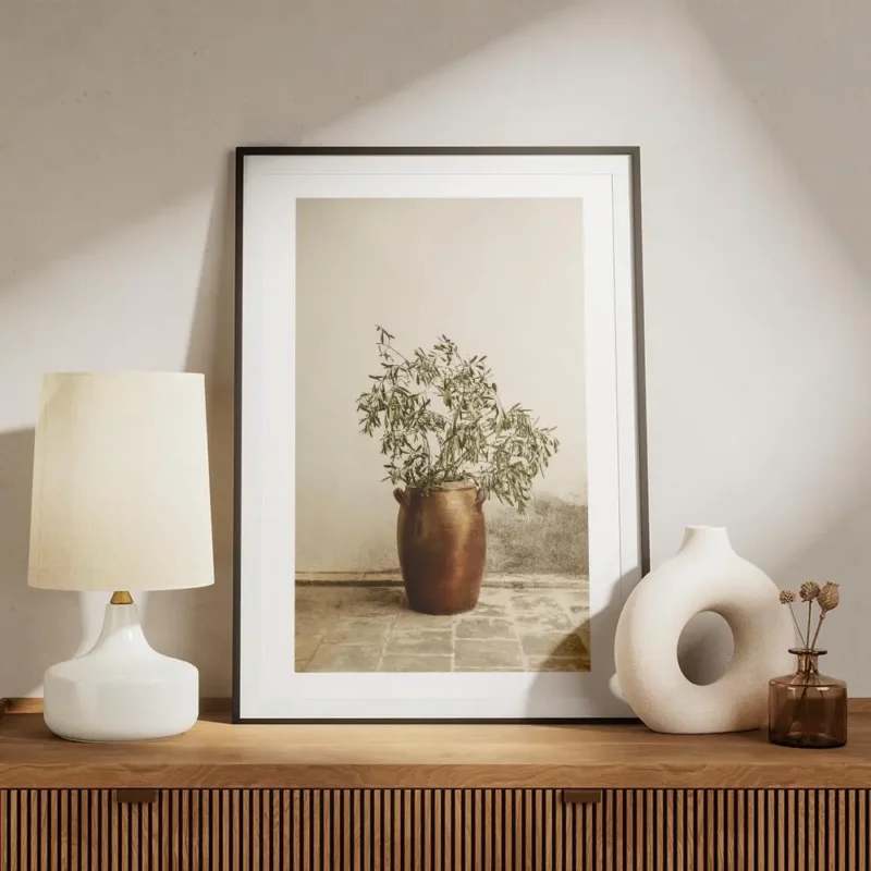 affiche botanique dun rameau dolivier dans un vase en terre cuite pose sur un so meuble.webp