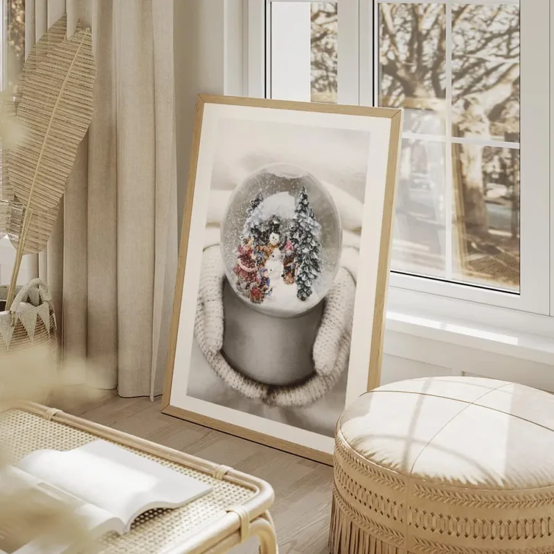 affiche boule a neige avec bonhomme de neige sapins et enfants tenue par des mai salon beige.webp