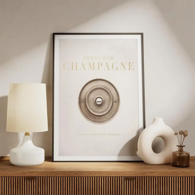 affiche champagne avec bouton en or et texte press for champagne sur un fond bei meuble.webp