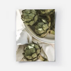 affiche dartichauts verts frais sur une assiette en ceramique blanche et un torc.webp