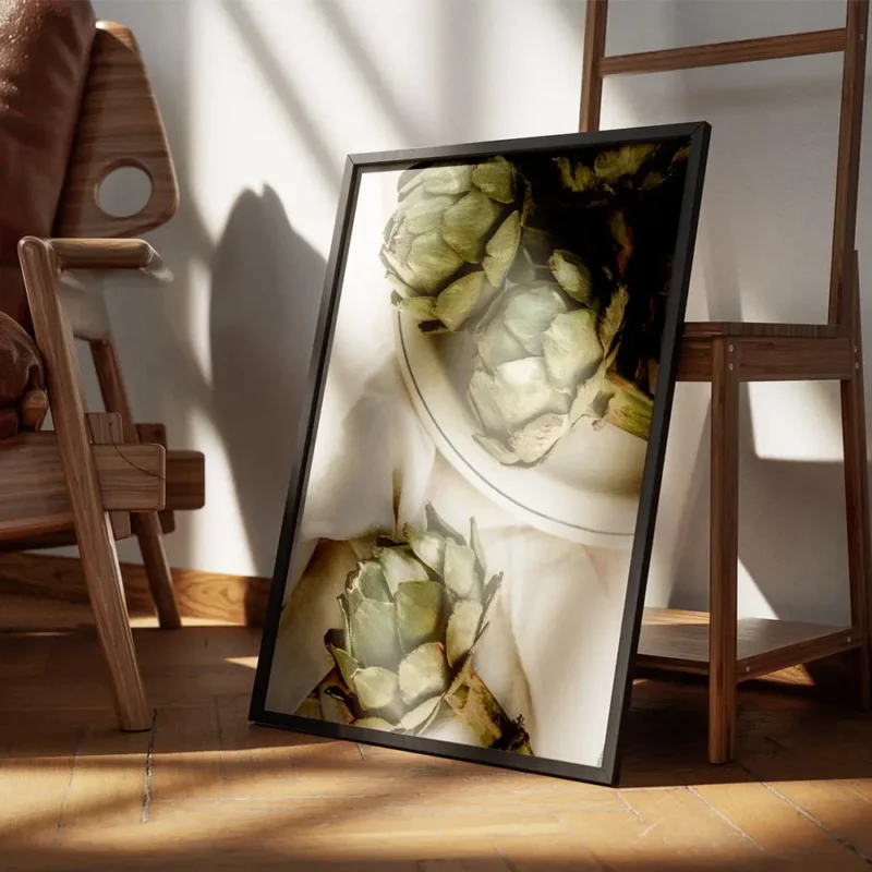affiche dartichauts verts frais sur une assiette en ceramique blanche et un torc encadre.webp