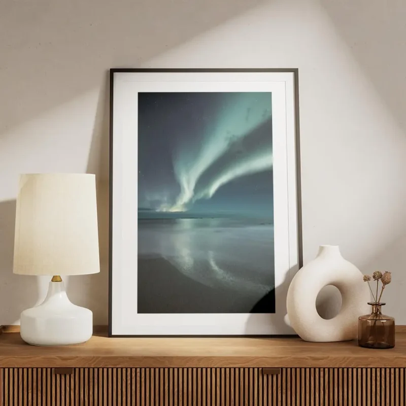 affiche daurores boreales bleues et vertes au dessus dune plage de sable sous un meuble.webp