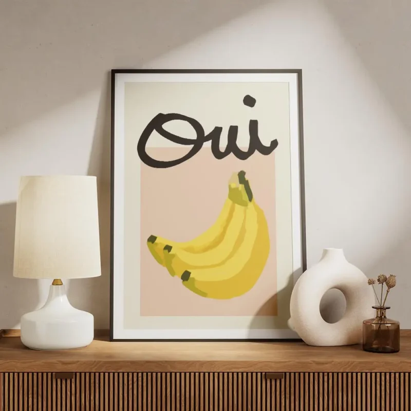 affiche de bananes jaunes sur carre rose et typographie noire oui sur fond beige meuble.webp