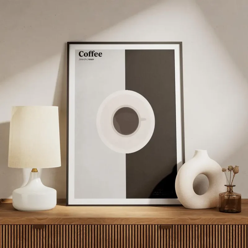 affiche de cafe graphique avec tasse et texte en noir et blanc sur fond gris et meuble.webp