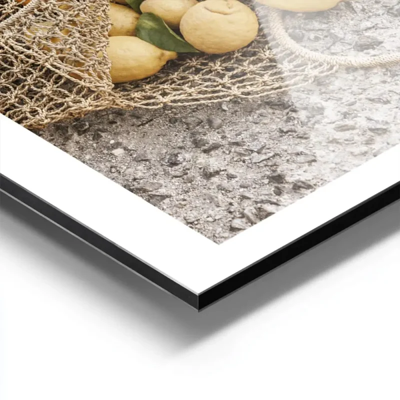 affiche de citrons jaunes dans un sac en filet sur un sol en pierre avec la mer aluminium.webp