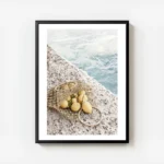 affiche de citrons jaunes dans un sac en filet sur un sol en pierre avec la mer avec cadre.webp
