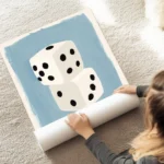 affiche de deux des blancs empiles avec des points noirs sur un fond bleu clair au sol.webp