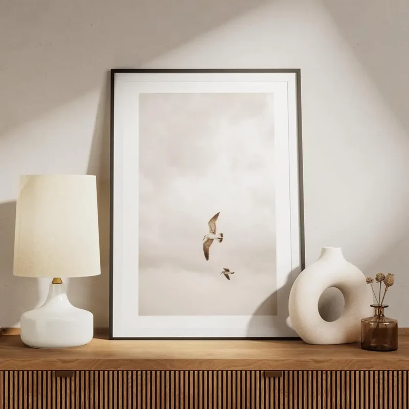 affiche de deux oiseaux volant dans un ciel nuageux de couleur beige meuble.webp
