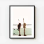 affiche de deux surfeuses avec une planche de surf faisant le signe de la paix s avec cadre.webp