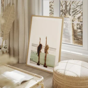 affiche de deux surfeuses avec une planche de surf faisant le signe de la paix s salon beige.webp