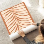 affiche de feuille beige abstraite avec un cercle rose sur fond orange rouille t au sol.webp