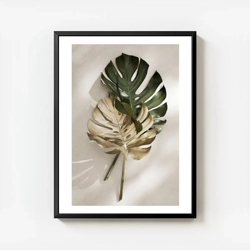affiche de feuilles de monstera une verte et une doree posees sur un fond clair avec cadre.webp