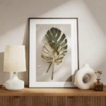 affiche de feuilles de monstera une verte et une doree posees sur un fond clair meuble.webp
