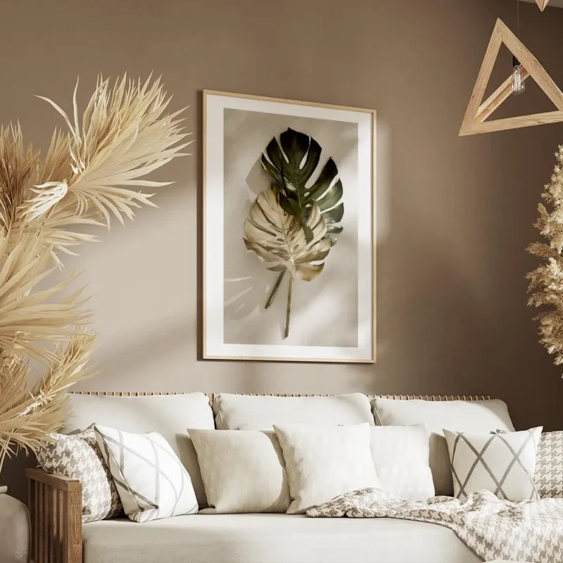 affiche de feuilles de monstera une verte et une doree posees sur un fond clair salon.webp