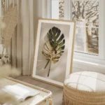 affiche de feuilles de monstera une verte et une doree posees sur un fond clair salon beige.webp