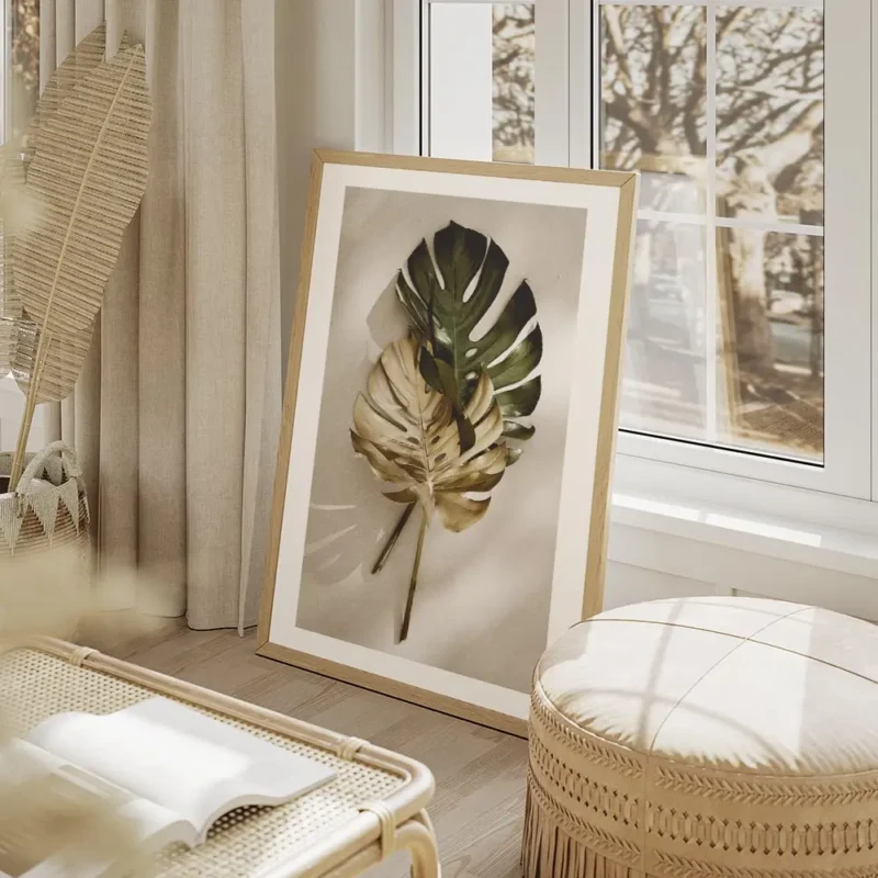 affiche de feuilles de monstera une verte et une doree posees sur un fond clair salon beige.webp