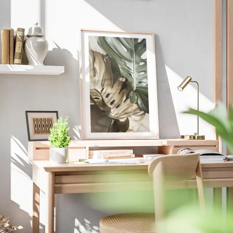 affiche de feuilles de monstera une verte et une doree sur un fond beige avec un bureau.webp