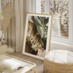 affiche de feuilles de monstera une verte et une doree sur un fond beige avec un salon beige.webp