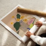 affiche de fleurs jaunes dans un vase beige avec des motifs bleus a cote dune pa enroule.webp