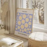 affiche de fleurs marguerite jaune souriantes sur fond bleu avec le texte the da salon beige.webp